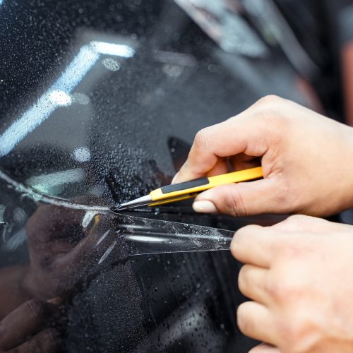 PPF technician installing PPF on the side of the car. PPF is a polyurethane, protective film that protects the paint from scratches